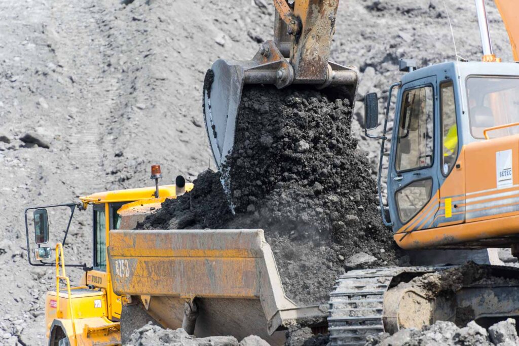 Excavator filling loading platform of truck with raw material